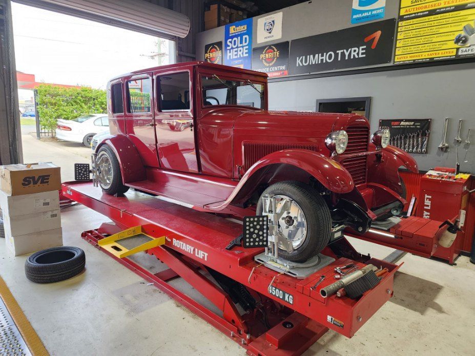 A Red Car is Sitting on Top of a Red Lift in a Garage — All Care Car Services Kumho Tyre Platinum Dealer in Kurri Kurri, NSW