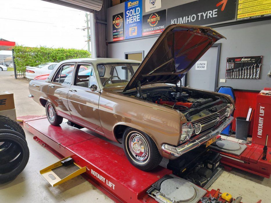 An Old Car is Sitting on a Lift in a Garage — All Care Car Services Kumho Tyre Platinum Dealer in Kurri Kurri, NSW