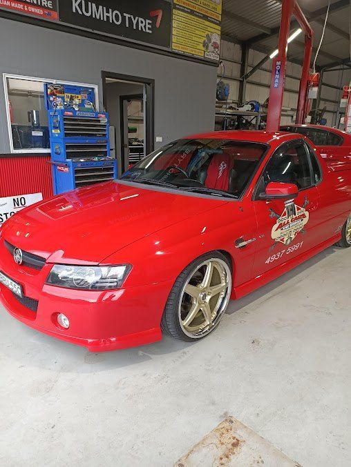 A Red Car is Parked in a Garage — All Care Car Services Kumho Tyre Platinum Dealer in Kurri Kurri, NSW