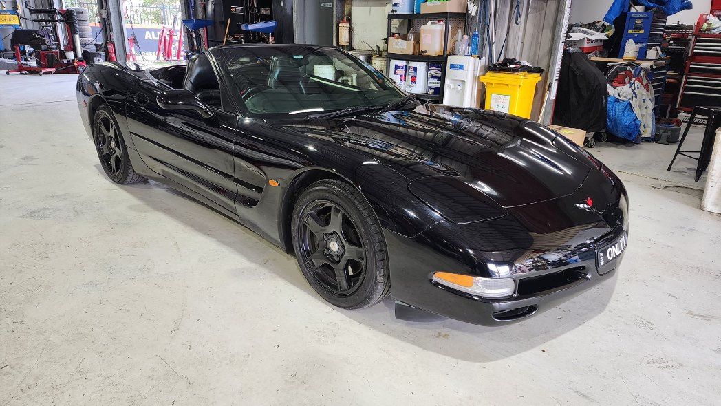 A Black Corvette Convertible is Parked in a Garage — All Care Car Services Kumho Tyre Platinum Dealer in Kurri Kurri, NSW