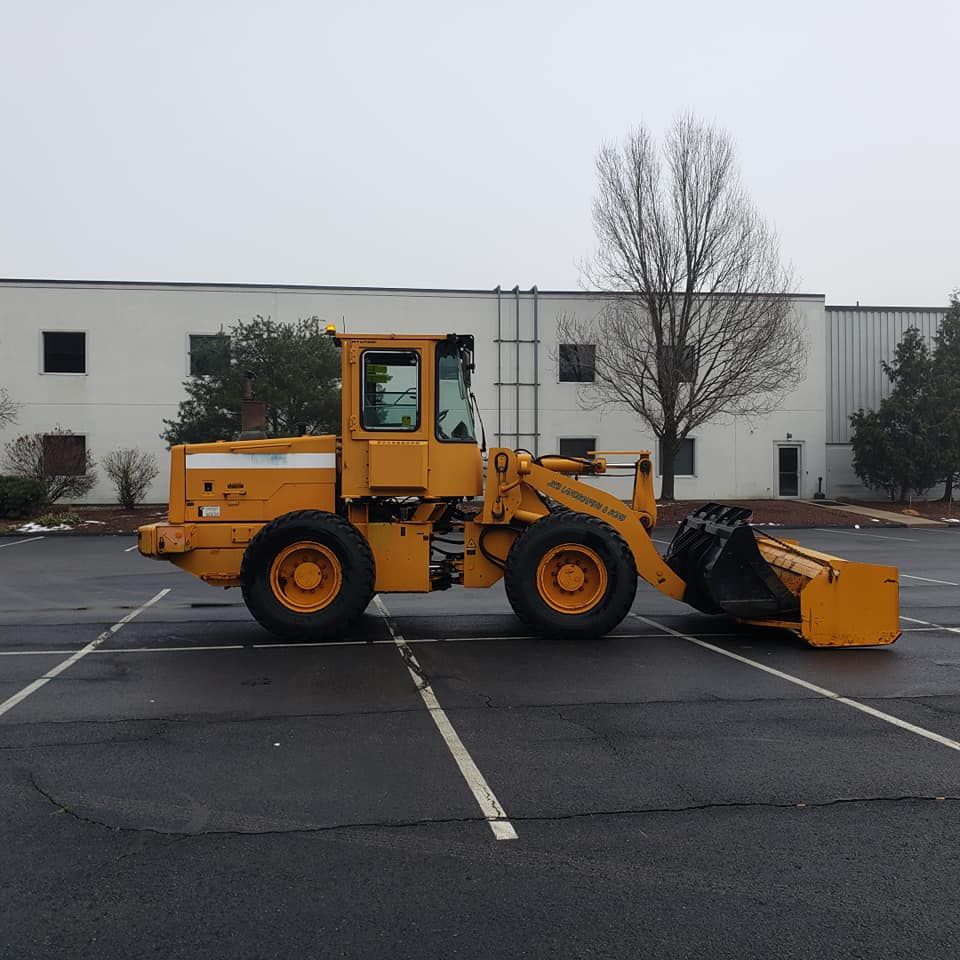 Yellow loader with bucket in commercial parking lot. Snow removal services for commercial properties and plazas. 
