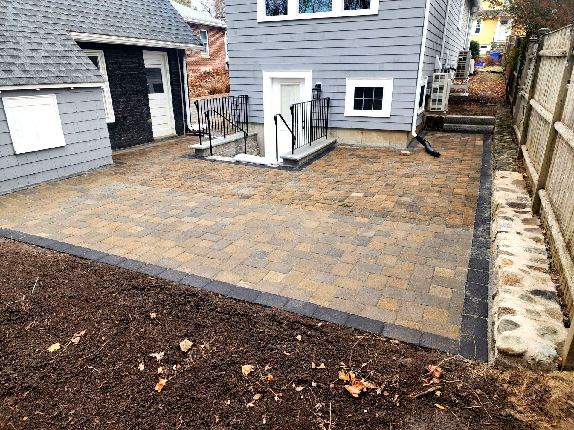 A new paver patio with tan and grey pavers. Also a new stone wall installed