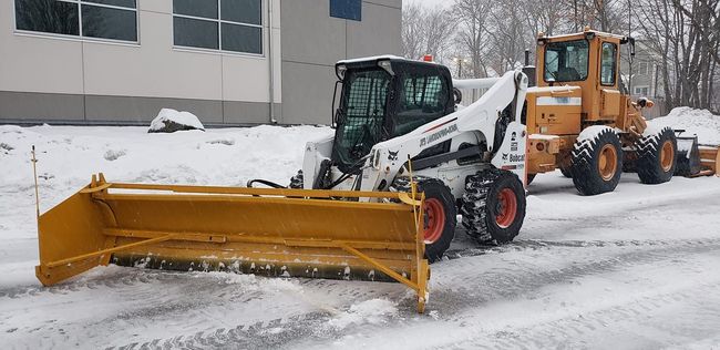 Photo of our snow plow lifting snow into a dump truck for commercial snow removal.