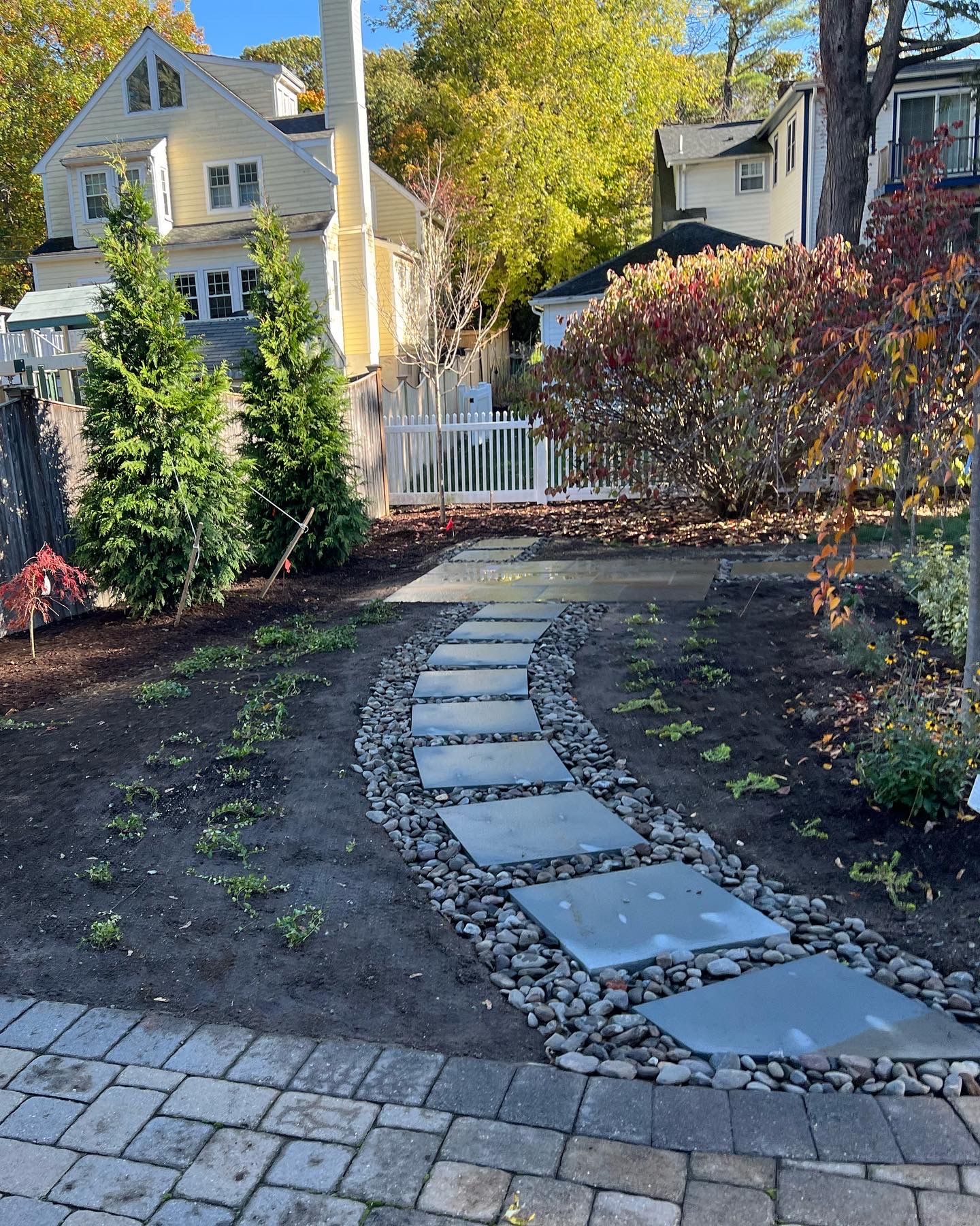 Landscape design in Lexington, MA. Decorative river rock, tree planting, stepping stones, and small bluestone patio install. 