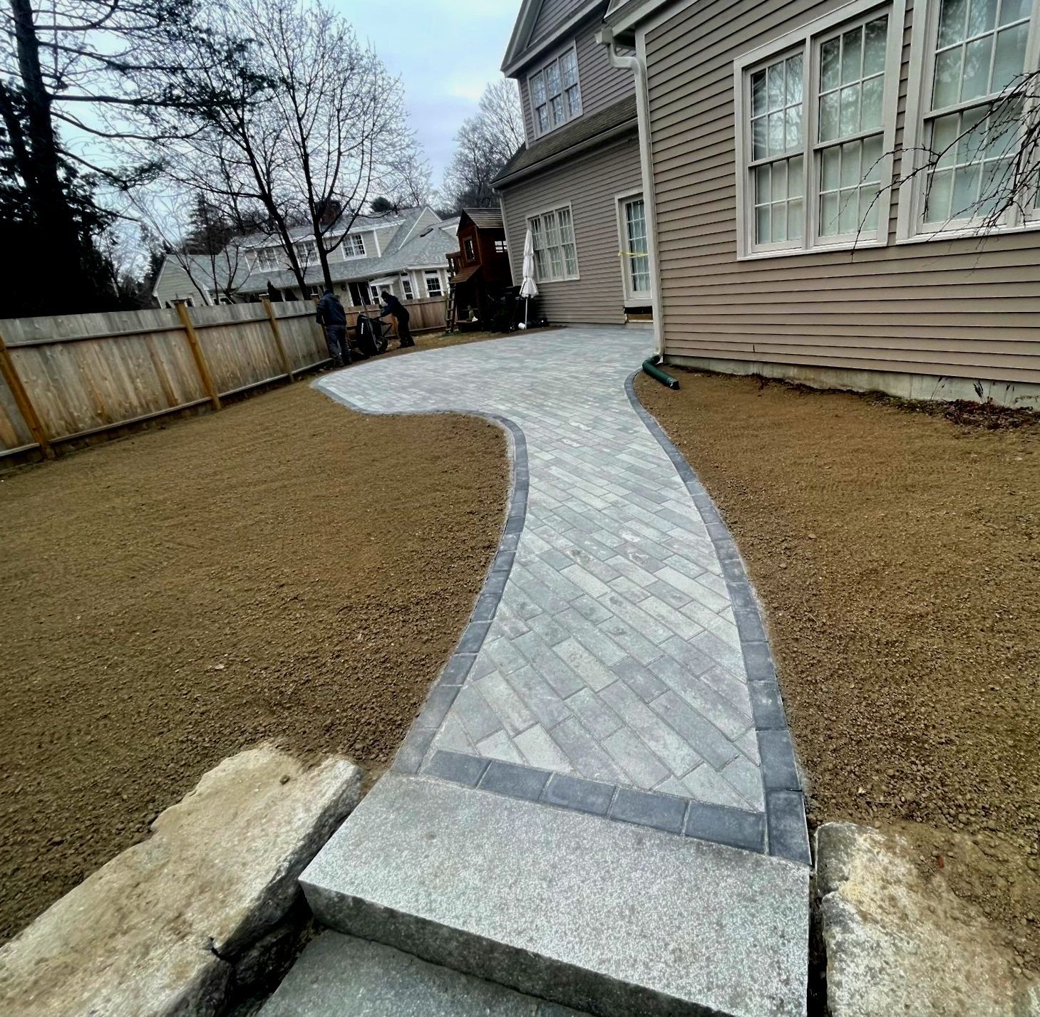 Paver walkway leading to a house with new patio installation and new lawn
