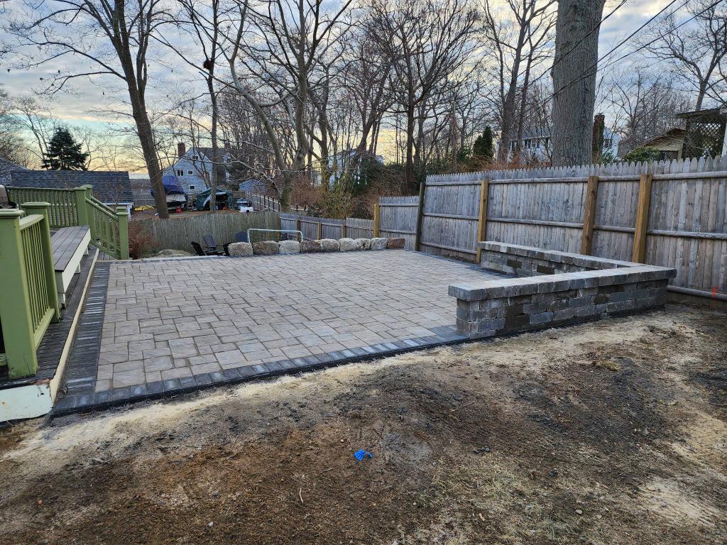 Hardscape design, backyard transformation in Gloucester, MA. Paver patio, seated retaining block wall, fire pit project. 