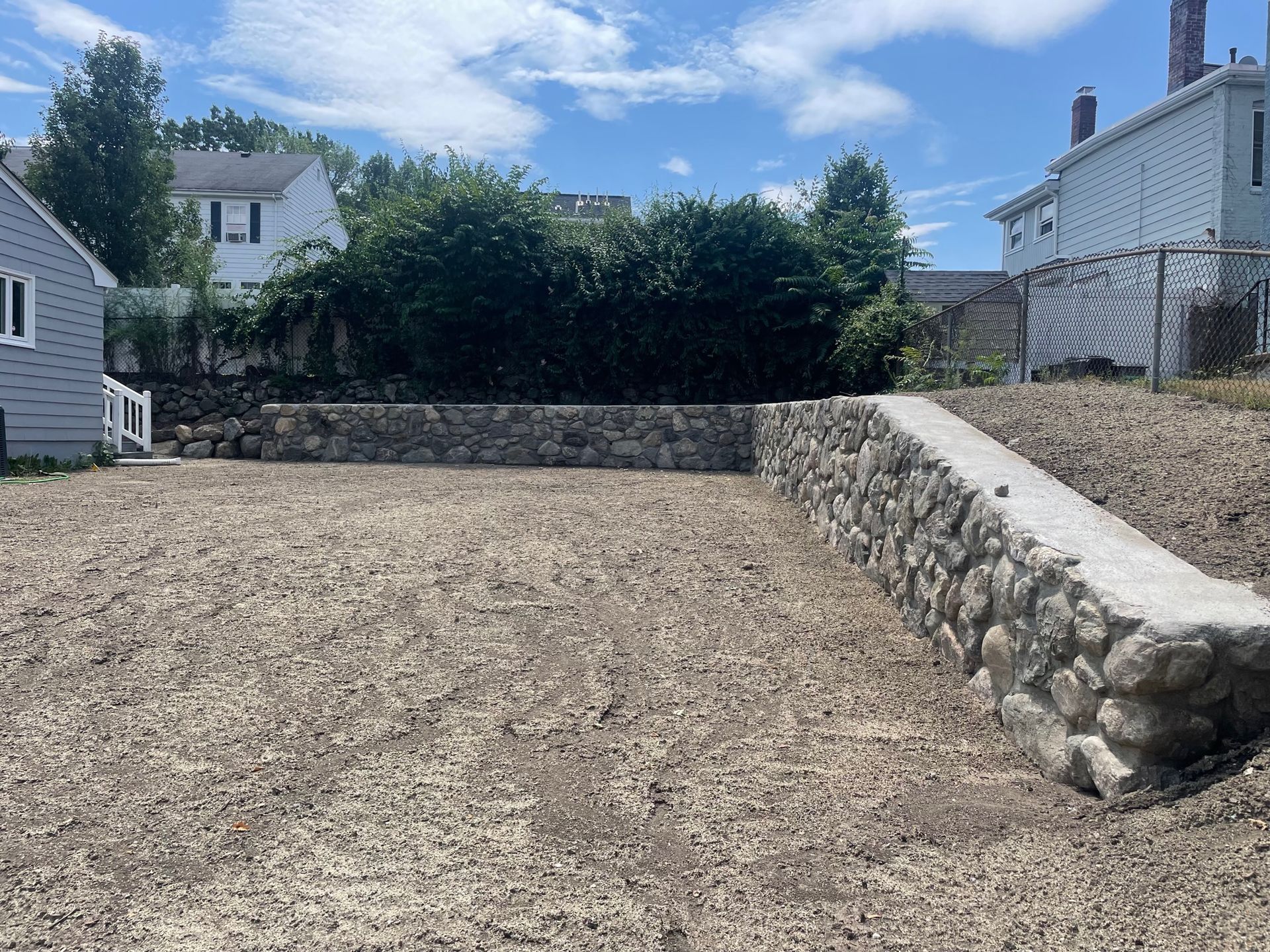 Stone wall installation. Stone wall design contractors in Arlington, MA. Excavation and grading project. Demolition of old stone wall and install new one. 