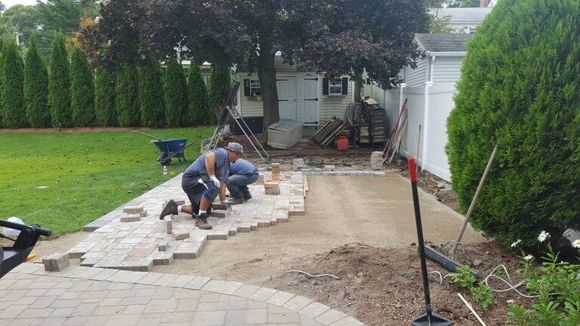 Photo of landscapers building a hardscape patio in a backyard in Burlington, MA. 