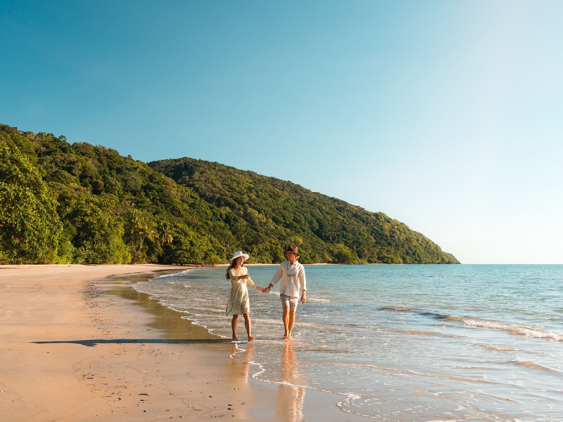 A couple enjoying their tour strolling along the waters edge at Cape Tribulation
