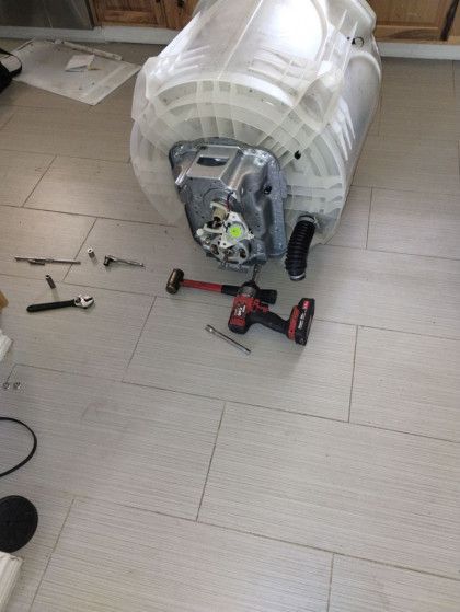 A water heater is being repaired on the floor with tools.