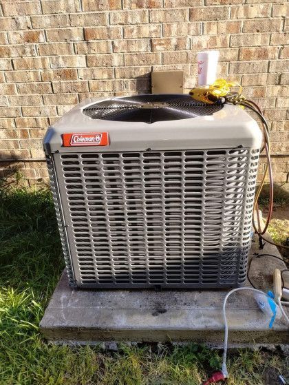 An air conditioner is sitting on the side of a brick building.