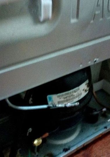 A compressor is sitting inside of a refrigerator.