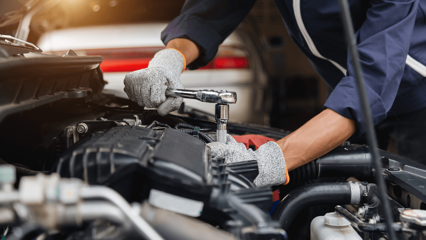 A mechanic doing an auto repair under the hood of a car in Thornton, CO