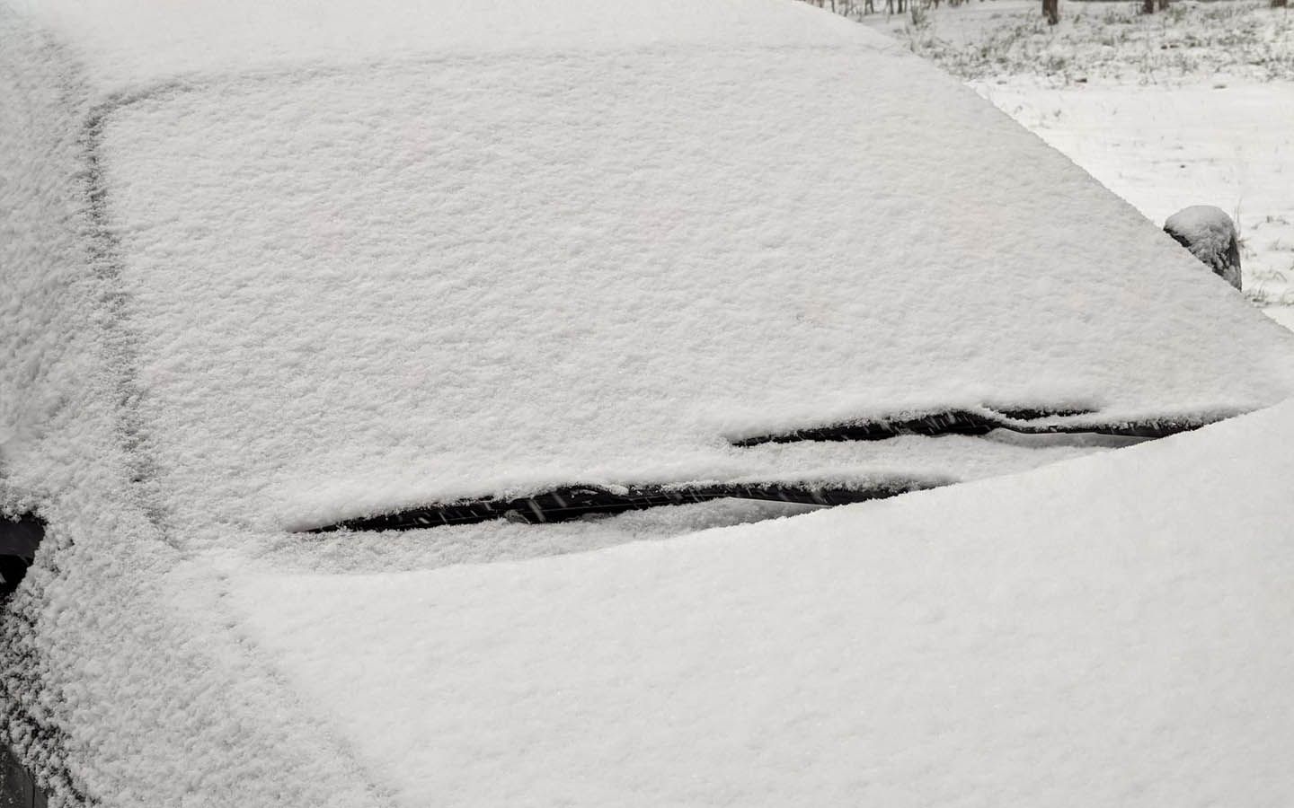 The windscreen of a car is covered in snow.