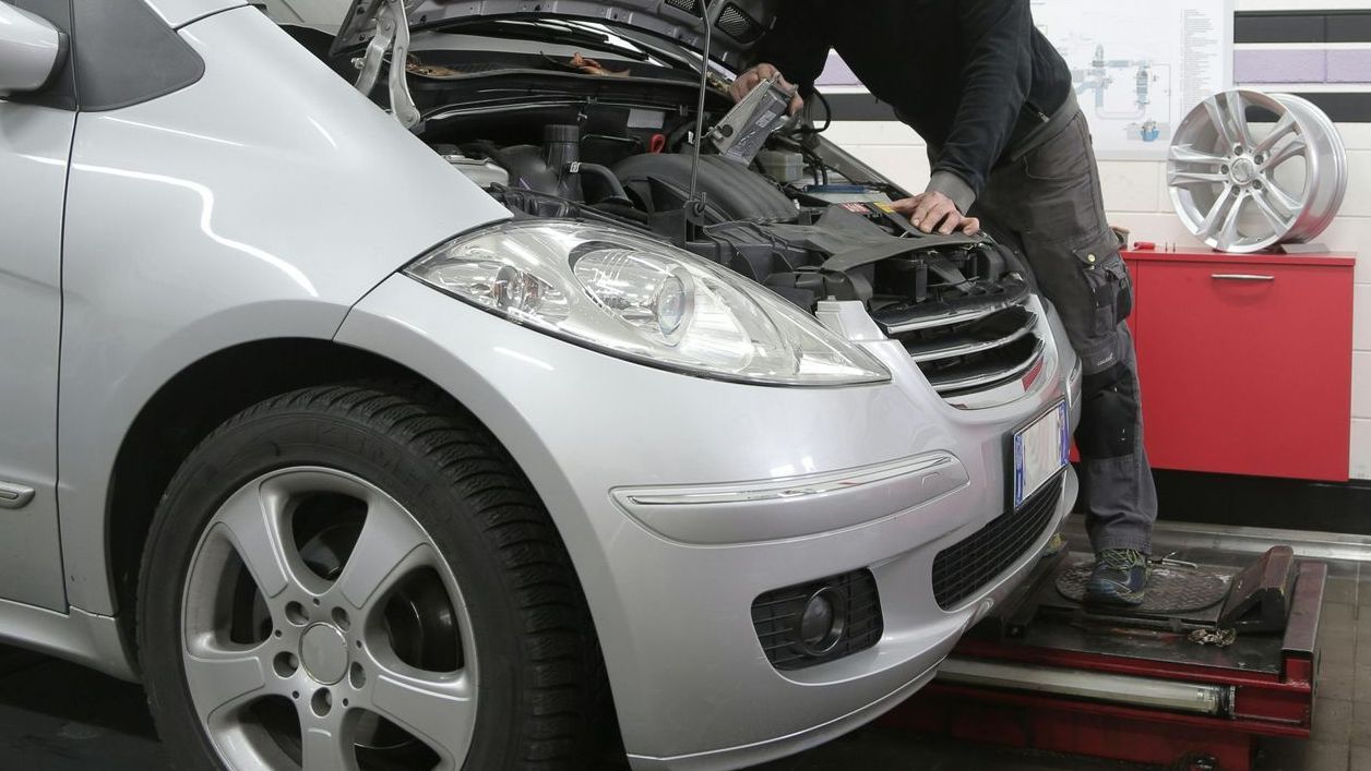 A man is working on the engine of a car.