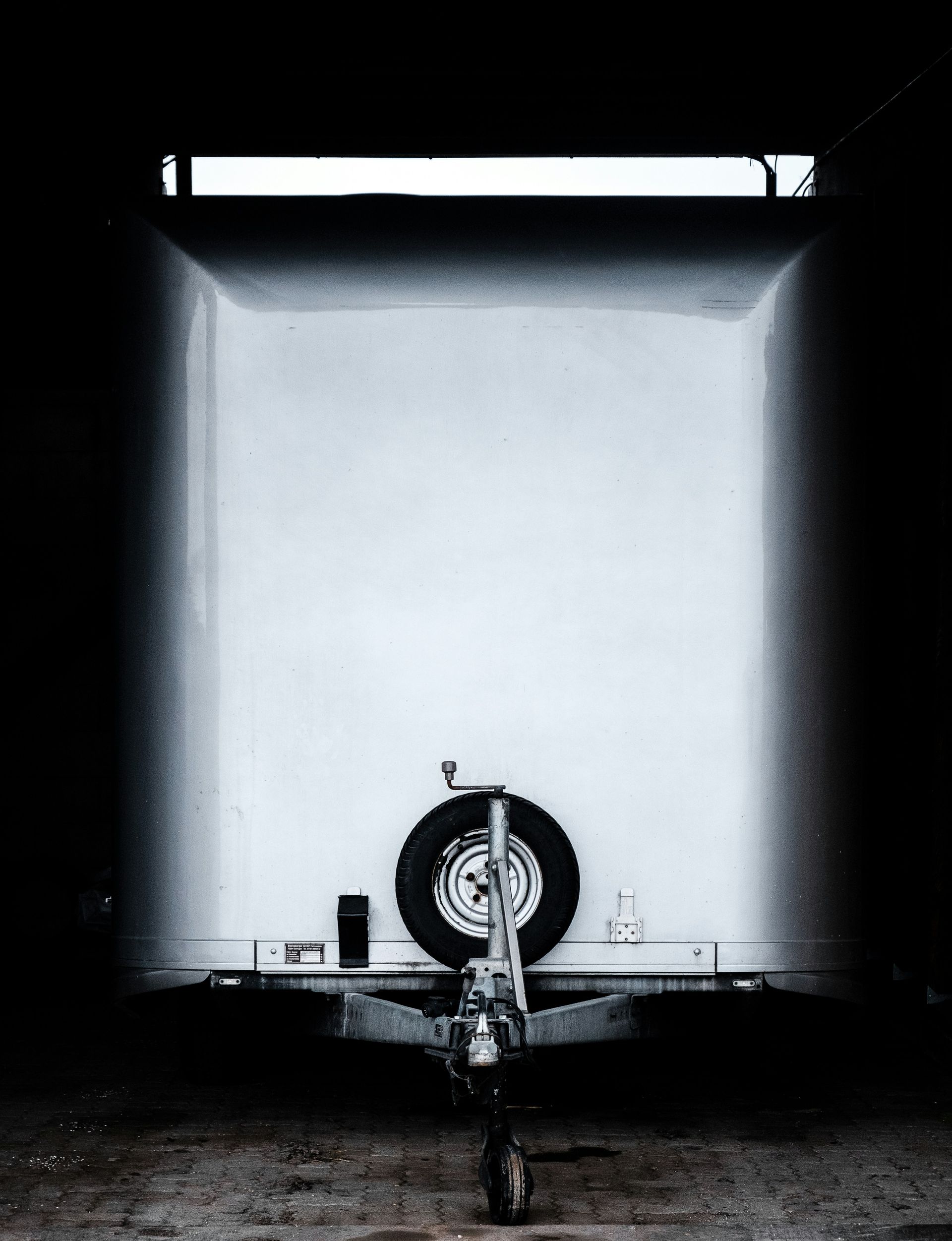 White trailer front, spare tire, dark garage interior.