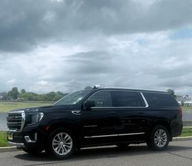 A black suv is parked on the side of the road on a cloudy day.