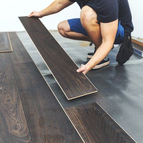 Residential Flooring — Man Placing Hardwood Floor in Muscle Shoals, AL
