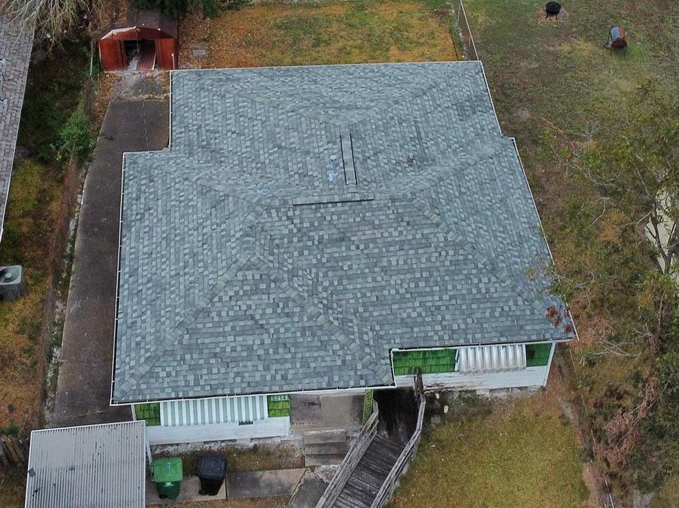 Overhead view of a house with a gray shingle roof, green trim, and a small shed in the yard.