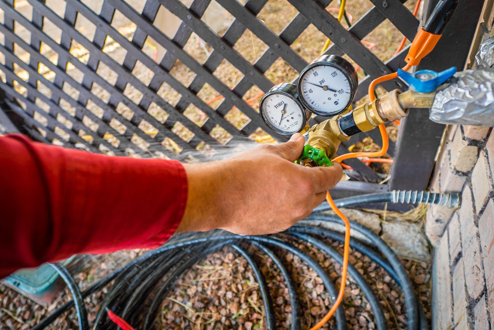 A man is working on a hose with a pressure gauge attached to it.