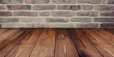 There is a wooden floor in front of a brick wall.