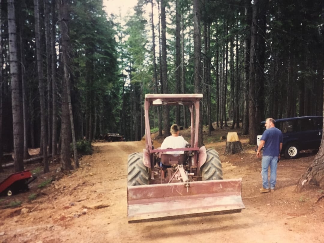 A man in heavy machinery clearing a road in the woods