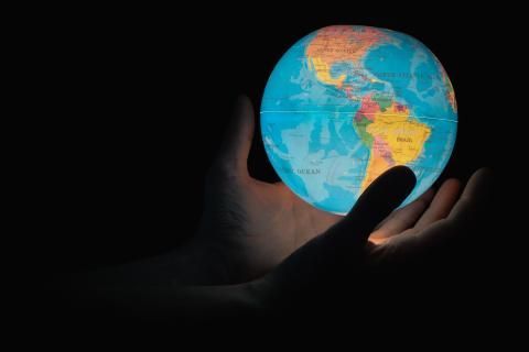 A person is holding a glowing globe in their hands.
