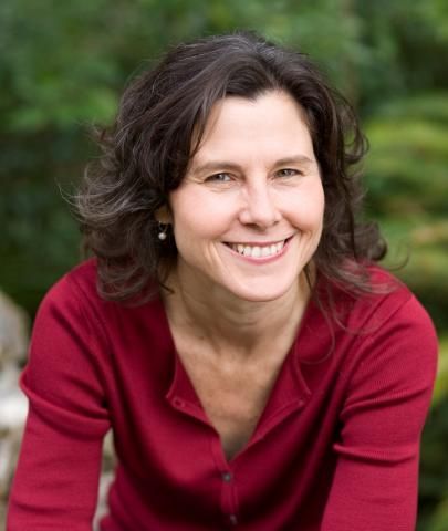 A woman in a red sweater is smiling for the camera.