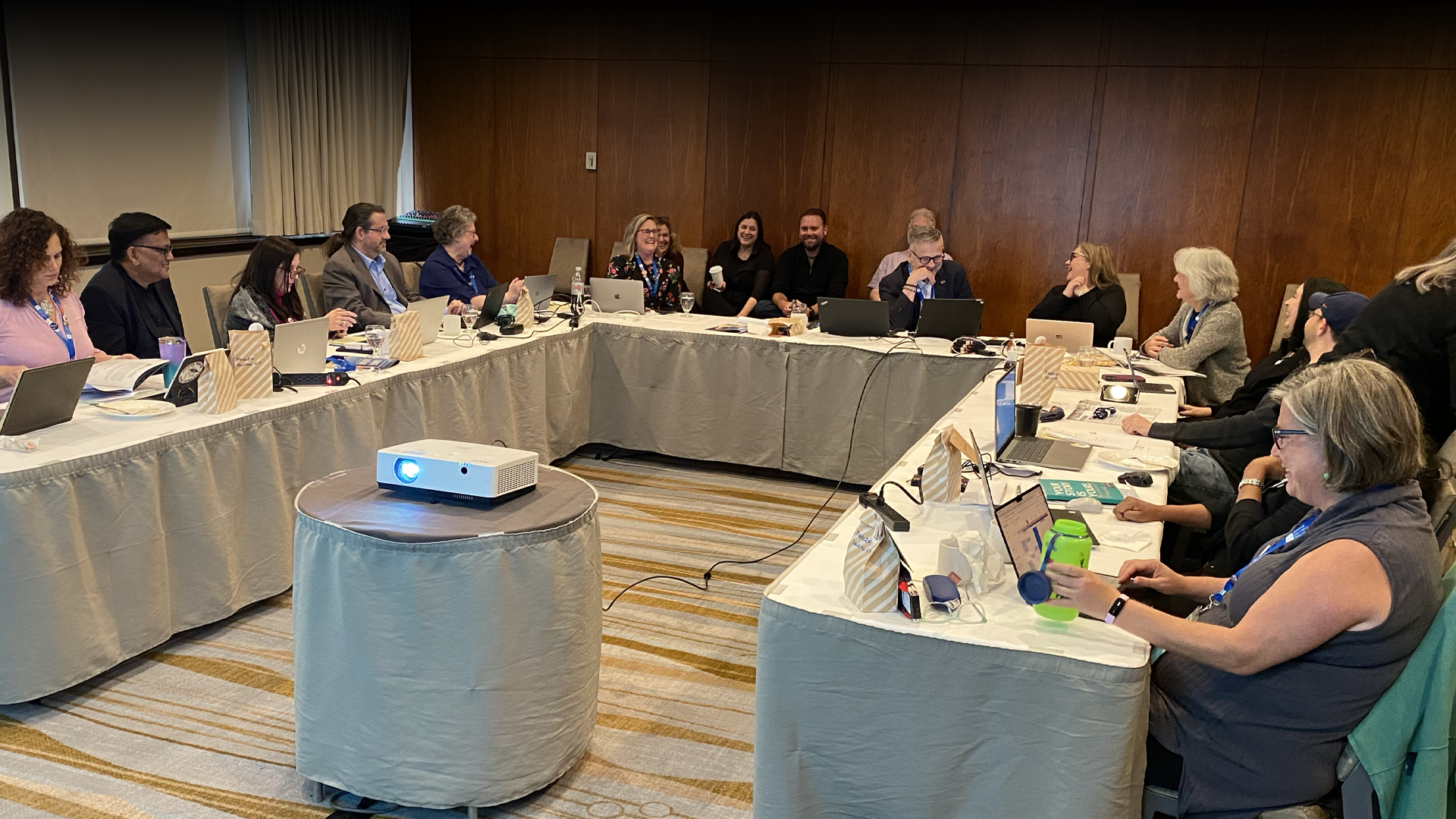 A group of people are sitting around a long table in a conference room.