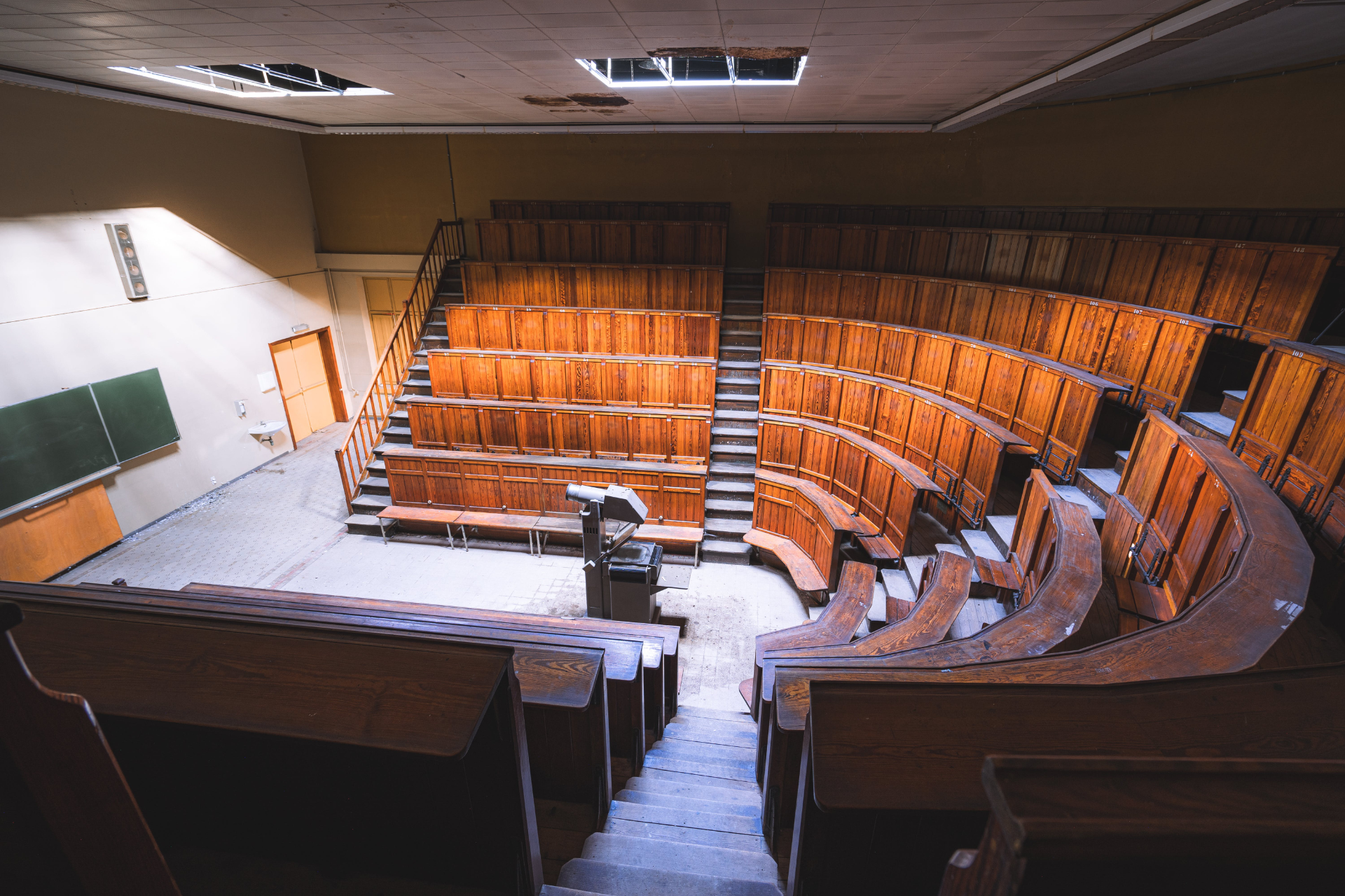An empty lecture hall with wooden seats and stairs.