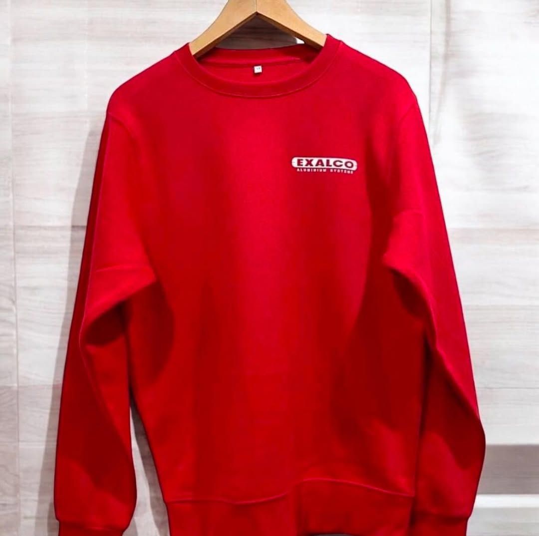 Ένα κόκκινο φούτερ κρέμεται σε μια ξύλινη κρεμάστρα