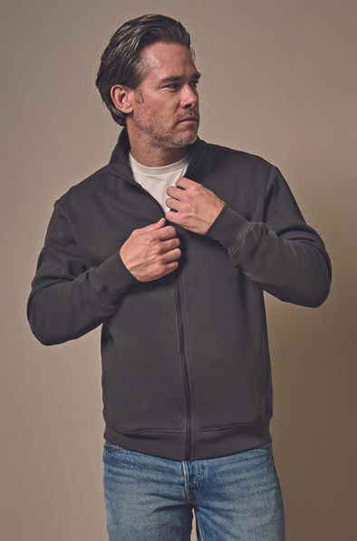 Ένας άντρας φοράει μαύρο μπουφάν και τζιν.