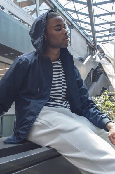 Ένας άντρας που φοράει ριγέ πουκάμισο και μπλε σακάκι κάθεται σε ένα κιγκλίδωμα.