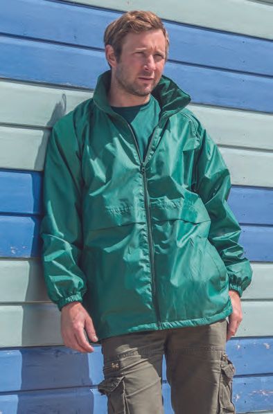 Ένας άντρας με πράσινο σακάκι ακουμπάει σε έναν μπλε και άσπρο τοίχο.