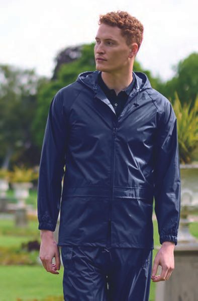 Ένας άντρας που φοράει μπλε αδιάβροχο και παντελόνι περπατάει σε ένα πάρκο.