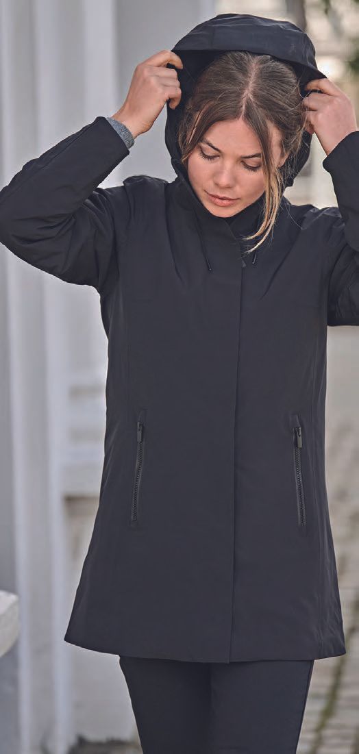 Μια γυναίκα φοράει μαύρο μπουφάν με κουκούλα.