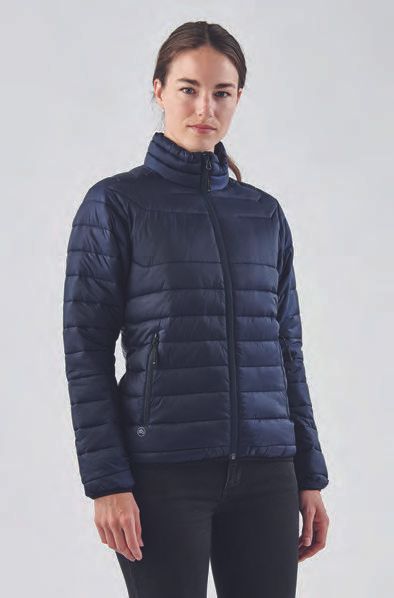 Μια γυναίκα φοράει ένα μπλε φουσκωτό σακάκι και ένα μαύρο παντελόνι.