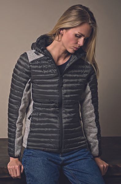 Μια γυναίκα που φοράει γκρι σακάκι και τζιν ακουμπάει σε ένα τραπέζι.