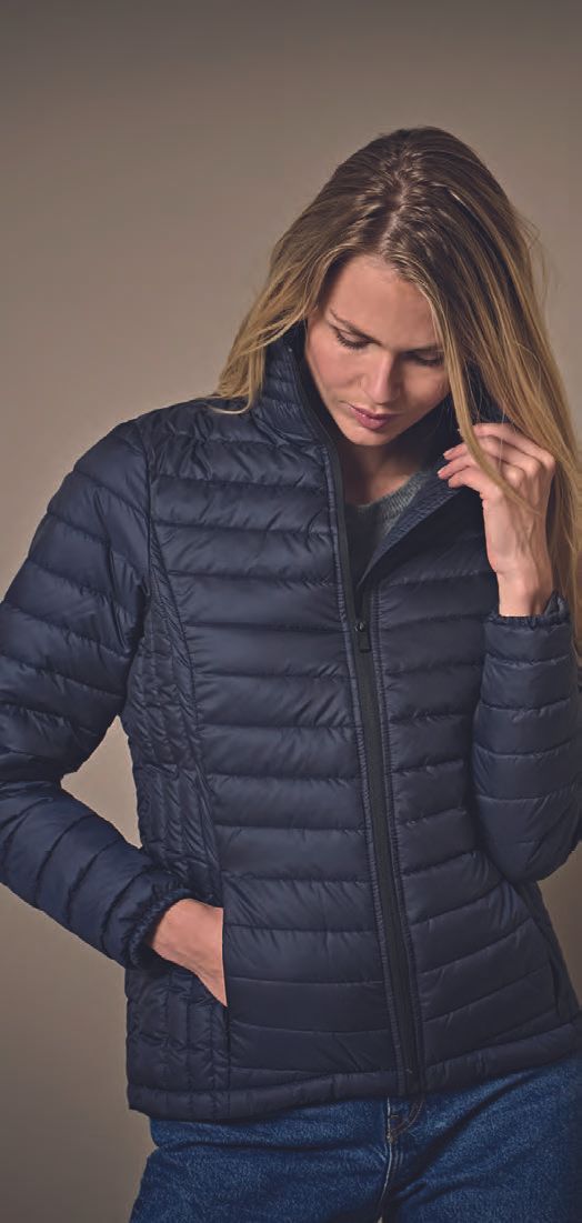 Μια γυναίκα φοράει ένα μπλε φουσκωτό μπουφάν και τζιν.