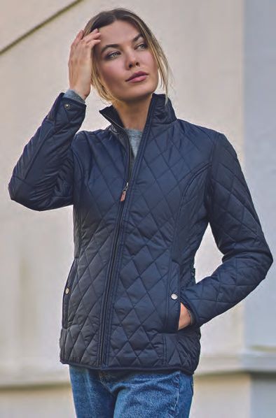 Μια γυναίκα φοράει ένα μαύρο καπιτονέ μπουφάν και τζιν.