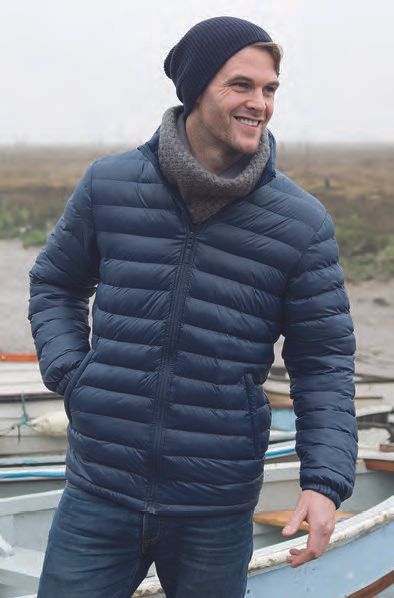 Ένας άντρας που φοράει μπλε μπουφάν και σκούφο στέκεται δίπλα σε μια βάρκα.