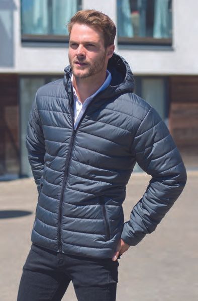 Ένας άντρας που φοράει ένα φουσκωτό μπουφάν με κουκούλα στέκεται μπροστά σε ένα κτίριο.