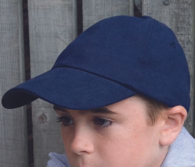 Ένα νεαρό αγόρι που φοράει ένα μπλε καπέλο του μπέιζμπολ στέκεται μπροστά από έναν ξύλινο φράχτη.