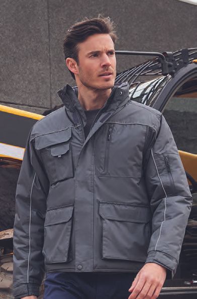 Ένας άντρας που φοράει γκρι σακάκι στέκεται μπροστά από ένα φορτηγό.