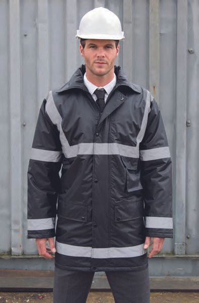 Ένας άντρας που φοράει κράνος και μαύρο μπουφάν στέκεται μπροστά από έναν φράχτη.