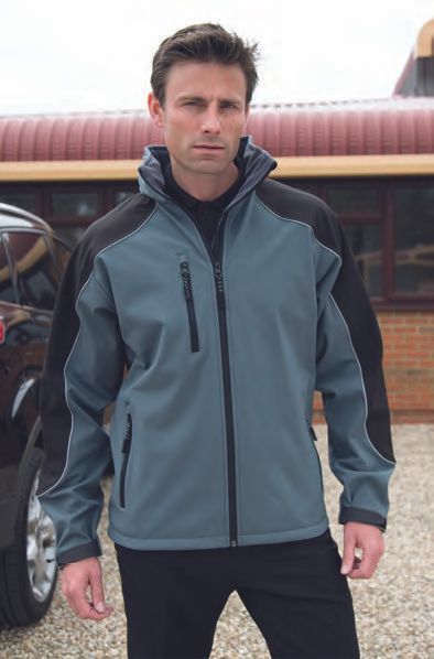 Ένας άντρας που φοράει γκρι και μαύρο μπουφάν στέκεται μπροστά από ένα αυτοκίνητο.