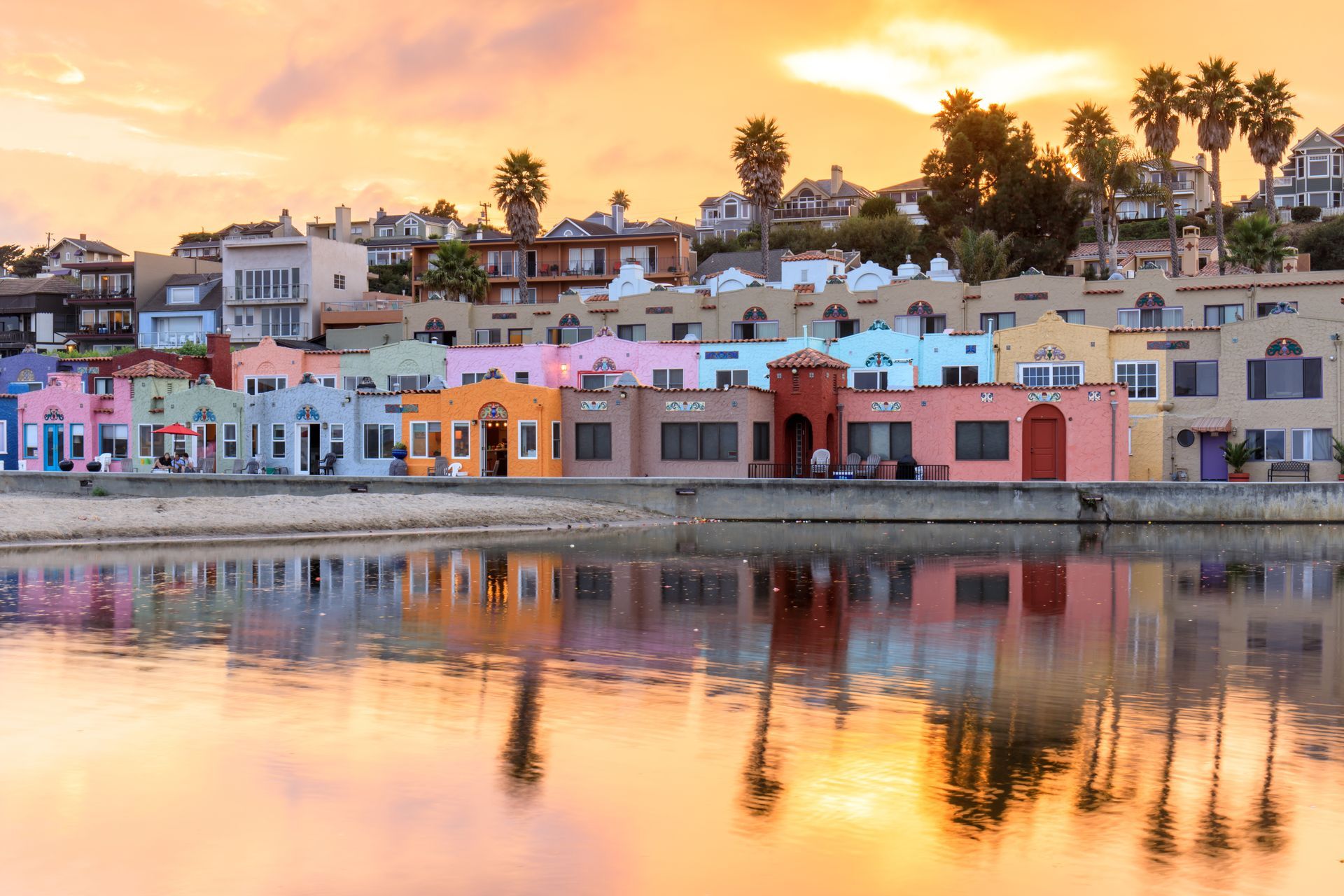 A row of colorful houses sit next to a body of water at sunset.