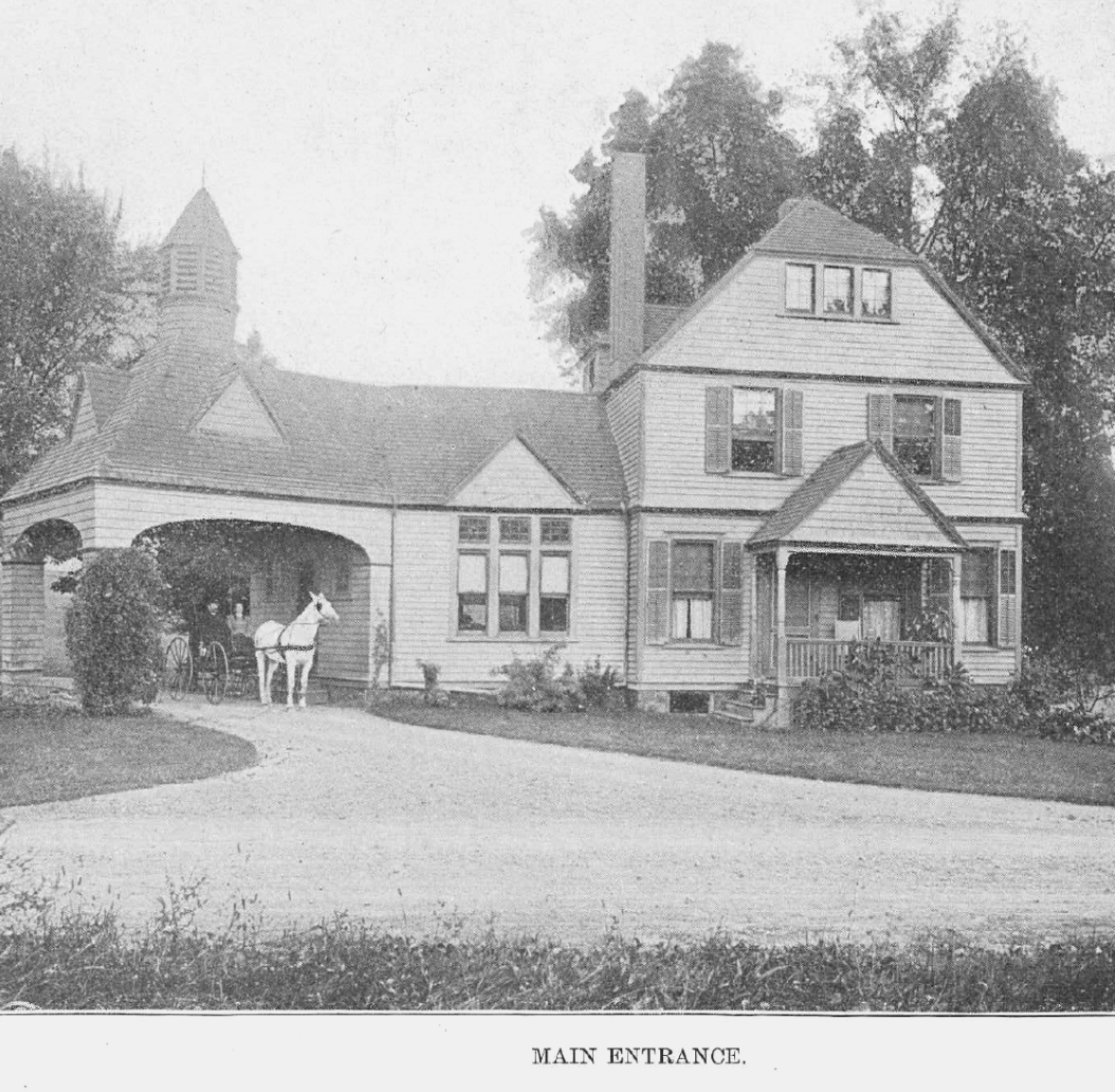 A black and white photo of a house with a horse in front of it