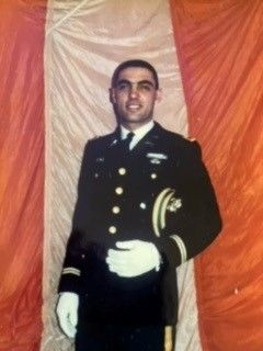 A man in a military uniform is standing in front of a red and white flag.  Michael Locascio, 1st Lieutenant, United States Army
(1940 - 2024), Fairview Cemetery Westfield, NJ