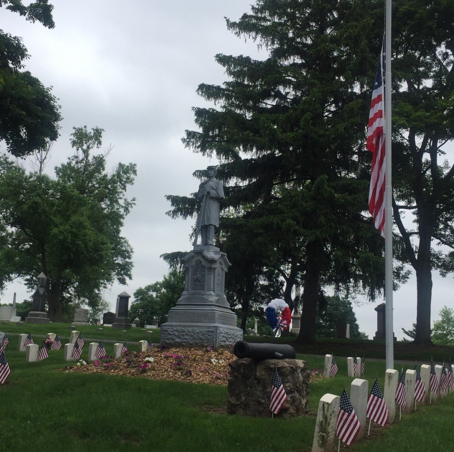 A cemetery with a statue and american flags